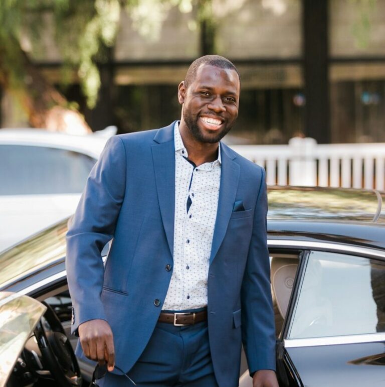 man in blue suit standing beside black car